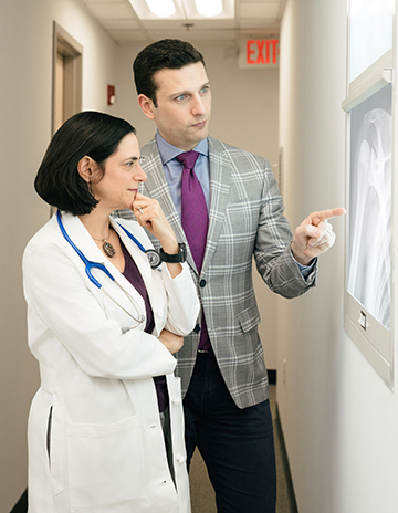 Two doctors looking at a patient's x-ray in the hallway of a building.