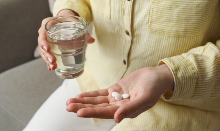 Patient holding calcium supplements to help manage osteoporosis symptoms.